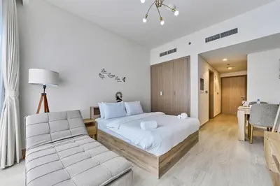 a bedroom with a bed and a chair and a table at Chic Studio in Azizi Riviera with Modern Amenities in Dubai