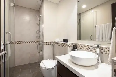 a white bathroom with a sink and a shower at Burj Khalifa View 1 Bedroom Apartment With Balcony For Up To 4 Person in Dubai