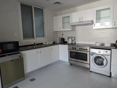 a kitchen with white cabinets and a washer and dryer at Stunning 2BR Apartment with Full Marina View in Dubai