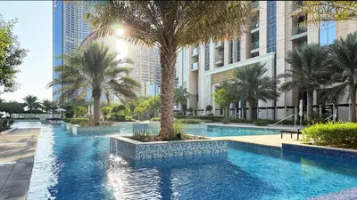 a swimming pool with palm trees and buildings at Canal-View Duplex in Dubai