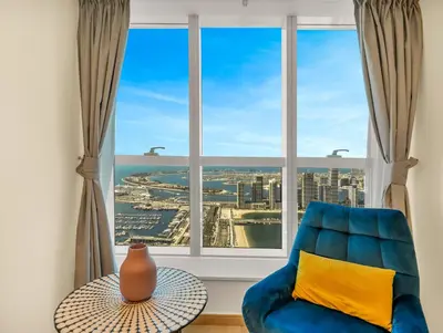 a blue chair in a room with a large window at Iconic Palm & Sea Views on 58th Floor Skyline Apt in Dubai