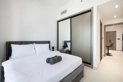 a bedroom with a large white bed with a bag on it at Luxury 2BR Burj View & Jacuzzi in Dubai