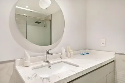 a white bathroom with a sink and a mirror at Luxe 1BR in Fairways East with Canal Views in Dubai
