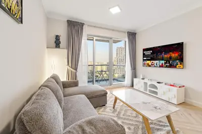 a living room with a couch and a tv at Luxe 1BR in Fairways East with Canal Views in Dubai