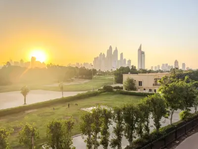 a view of a city skyline at sunset at Luxe 1BR in Fairways East with Canal Views in Dubai