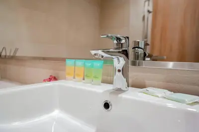 a bathroom sink with a faucet and two glasses on it at Cozy Studio with Garden Views in Nad Al Sheba in Dubai