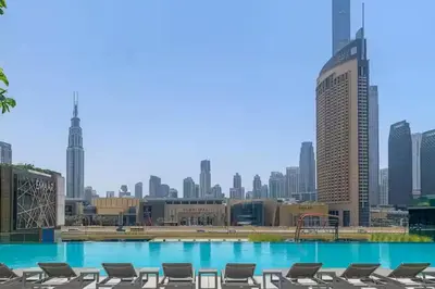 a swimming pool with chairs and a city skyline at Vogue Downtown Views II with Direct Access to Dubai Mall Via a Climate Controlled Bridge, Two Bedroom Apartment with Balcony and Burj Khalifa View in Dubai