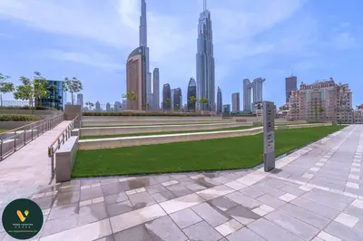 a park with benches and grass in front of a city at Vogue Downtown Views II with Direct Access to Dubai Mall Via a Climate Controlled Bridge, Two Bedroom Apartment with Balcony and Burj Khalifa View in Dubai