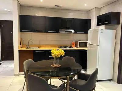 a kitchen with a table with chairs and a refrigerator at Cozy 1BHK Apartment-Dubai Marina in Dubai