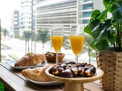 a table with two glasses of orange juice and pastries at Chic 1 Bedroom on Private Beach in Dubai Harbour in Dubai