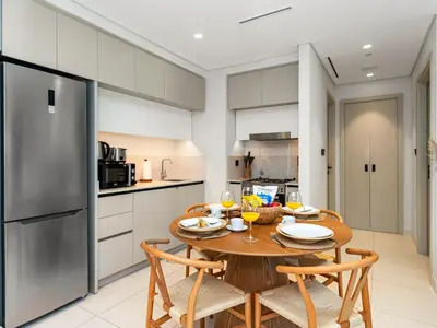a kitchen and dining room with a wooden table and chairs at Chic 1 Bedroom on Private Beach in Dubai Harbour in Dubai