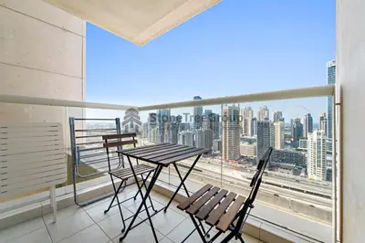 a balcony with a table and chairs and a view of a city at High-floor 2BR at Palladium, JLT - Near Metro in Dubai