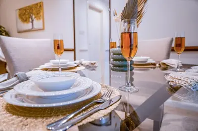 a glass table with plates and wine glasses on it at The Nest by Beds & Company in Dubai