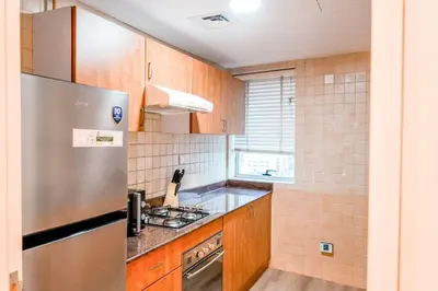 a kitchen with wooden cabinets and a stainless steel refrigerator at The Nest by Beds & Company in Dubai