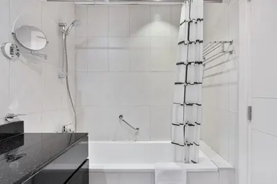 a white bathroom with a shower and a bath tub at Urban Sanctuary Studio with Pool, Gym and Playground in Dubai