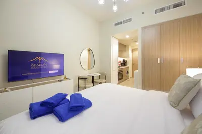 a bedroom with a white bed with blue bow ties on it at NewArabian Azizi Riviera Studio in Dubai