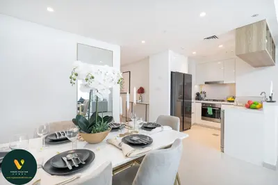 a white kitchen and dining room with a table and chairs at Vogue Downtown Views II with Direct Access to Dubai Mall Via a Climate Controlled Bridge, Two Bedroom Apartment with Balcony and Burj Khalifa View in Dubai