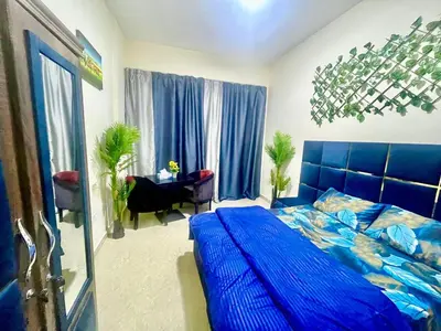 a bedroom with a large blue bed and a desk at Brand New Studio Near ADCB Metro in Dubai
