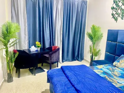 a bedroom with a table and a bed and blue curtains at Brand New Studio Near ADCB Metro in Dubai