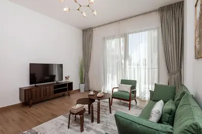a living room with a green couch and a tv at La Mer 1bedroom Private Beach in Dubai