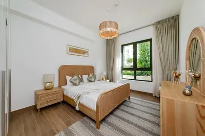 a bedroom with a bed and a dresser and a window at La Mer 1bedroom Private Beach in Dubai