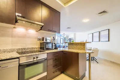 a kitchen with brown cabinets and a counter top at Stylish 2BR in Sky Gardens, DIFC by Deluxe Holiday Homes in Dubai