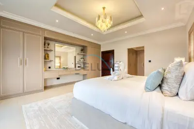 a bedroom with a large white bed and a chandelier at Immaculate 4BR Villa with Assistant Room and Private Pool at Frond O Palm Jumeirah by Deluxe Holiday Homes in Dubai