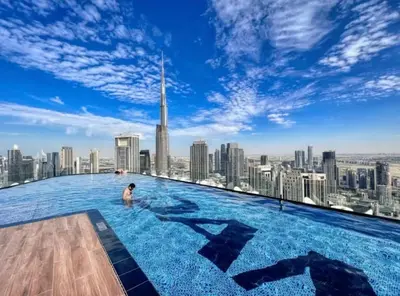a man in the infinity pool at the dubai skyline at Spectacular 2 Bed Downtown I Highest Infiniti Pool in Dubai