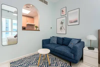 a living room with a blue couch and a table at White Sage Renovated Studio Nxt to Metro in Dubai