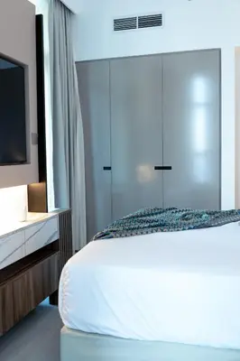 a bedroom with a white bed with a dresser and a tv at Lusso Hometels Missoni Business Bay in Dubai