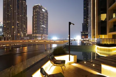 a couple of chairs sitting on a balcony in a city at night at Lusso Hometels Missoni Business Bay in Dubai