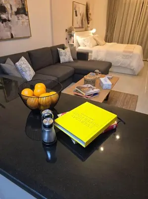 a living room with a table with a bowl of oranges at Modern Studio Apartment in JVC, behind Circle Mall in Dubai