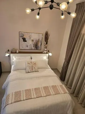 a bedroom with a large white bed with a chandelier at Modern Studio Apartment in JVC, behind Circle Mall in Dubai