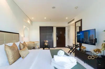a bedroom with a white bed and a large screen tv at The Modern in Dubai