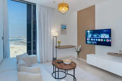 a living room with a white couch and a tv at Modern 1br Oasis in Sobha Creek Vista A, MBR City - Allsopp & Allsopp in Dubai