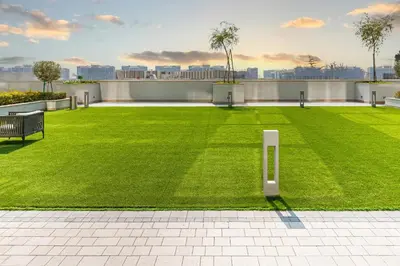 a large green lawn with a bench on a building at Modern 1br Oasis in Sobha Creek Vista A, MBR City - Allsopp & Allsopp in Dubai
