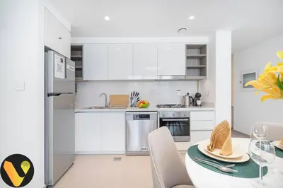 a kitchen with white cabinets and a table and chairs at Vogue Downtown Views II with Direct Access to Dubai Mall Via a Climate Controlled Bridge, One Bedroom Apartment with Balcony and City View in Dubai