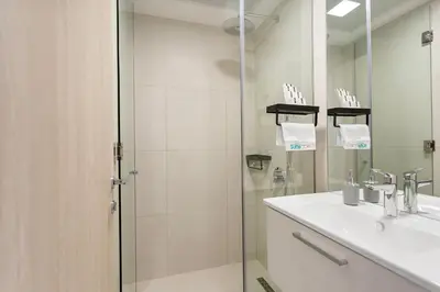 a bathroom with a shower and a sink and a mirror at Perfect Getaway modern Studio in Luma 22 - JVC in Dubai