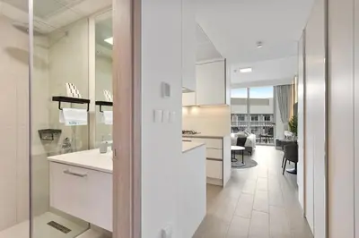 a kitchen with white cabinets and a dining room at Perfect Getaway modern Studio in Luma 22 - JVC in Dubai