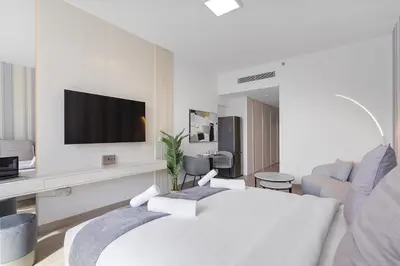 a white hotel room with a bed and a tv at Perfect Getaway modern Studio in Luma 22 - JVC in Dubai