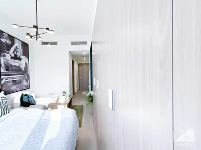 a bedroom with a white bed and a white cabinet at Bright Studio in Azizi Riviera Perfect City Escape in Dubai