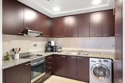 a kitchen with wooden cabinets and a washer and dryer at Silkhaus Sky Gardens Chic Studio in DIFC Living in Dubai