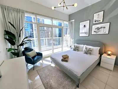 a bedroom with a bed and a large window at SUNRISE HOMES - 2 BR with Panoramic Marina Views in Dubai