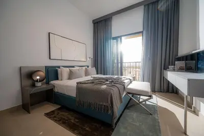 a bedroom with a bed with a desk and a window at Spacious Unit With Burj Khalifa View in Dubai