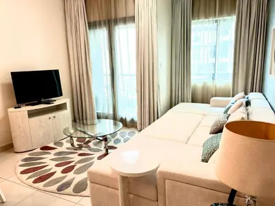 a living room with a white couch and a tv at 1BHK in Damac Masion mall street in Dubai