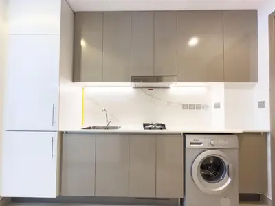 a white kitchen with a washing machine in it at Furnished Studio Azizi Riviera 3 in Dubai