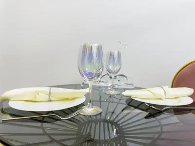 a glass table with two wine glasses and napkins at Studio in Azizi Riviera Dubai in Dubai