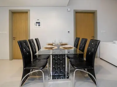 a dining room with a glass table and black chairs at 50th Floor 2 Bed with Burj and Sea view in Dubai