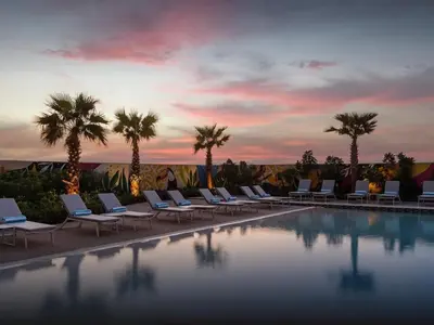 a pool with lounge chairs and palm trees at sunset at 50th Floor 2 Bed with Burj and Sea view in Dubai