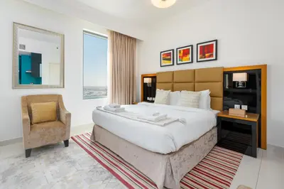 a bedroom with a large bed and a chair at Vacay Lettings - DAMAC Capital Bay Tower in Dubai